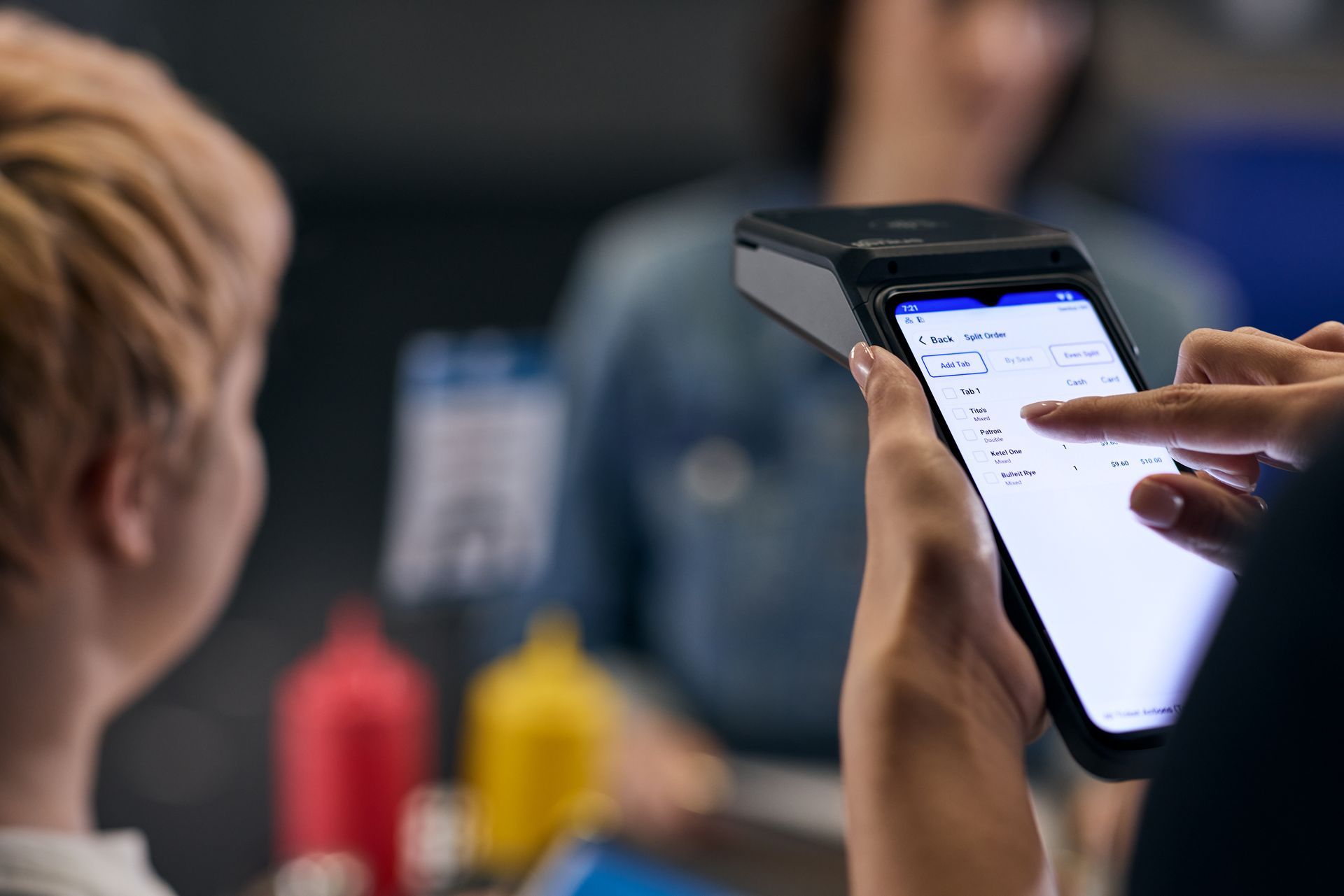 Black Heartland point-of-sale device, front view displaying a touch screen, with a printer attached to the top.