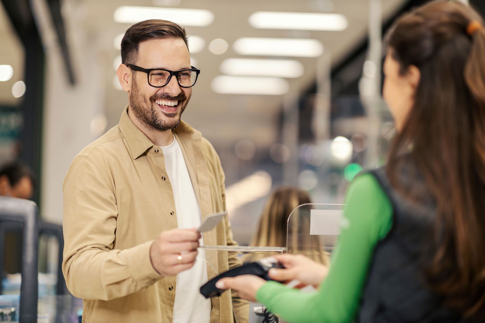 Man smiling, paying at checkout counter; store interior.