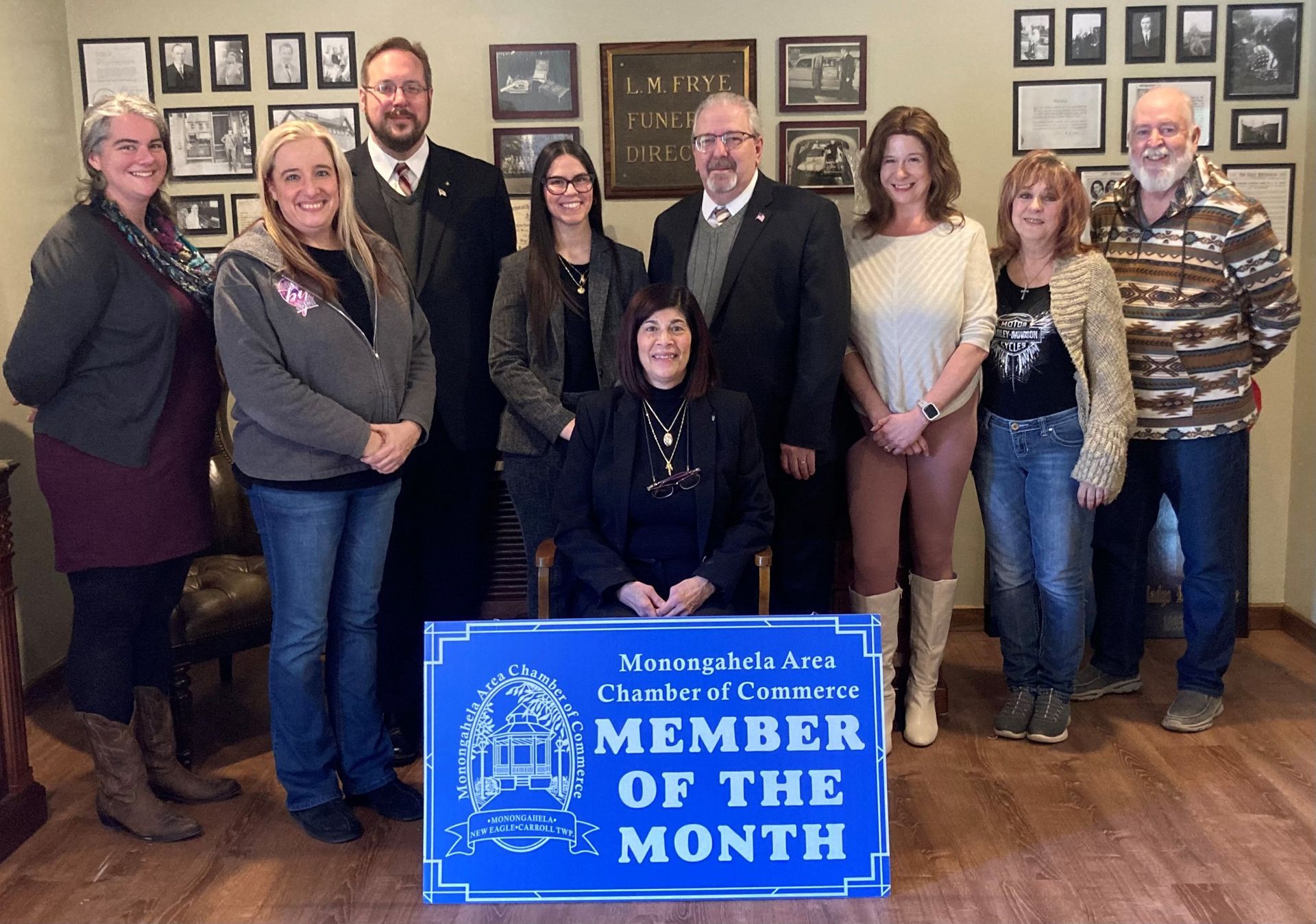 Group photo in an office with a blue “Member of the Month” sign in front