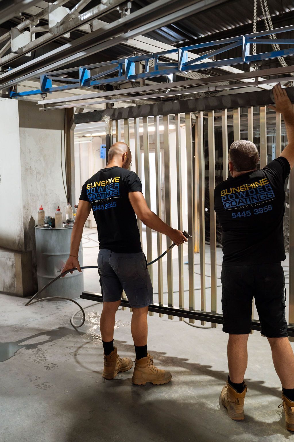Two workers installing a vertical metal frame inside a partially built room.