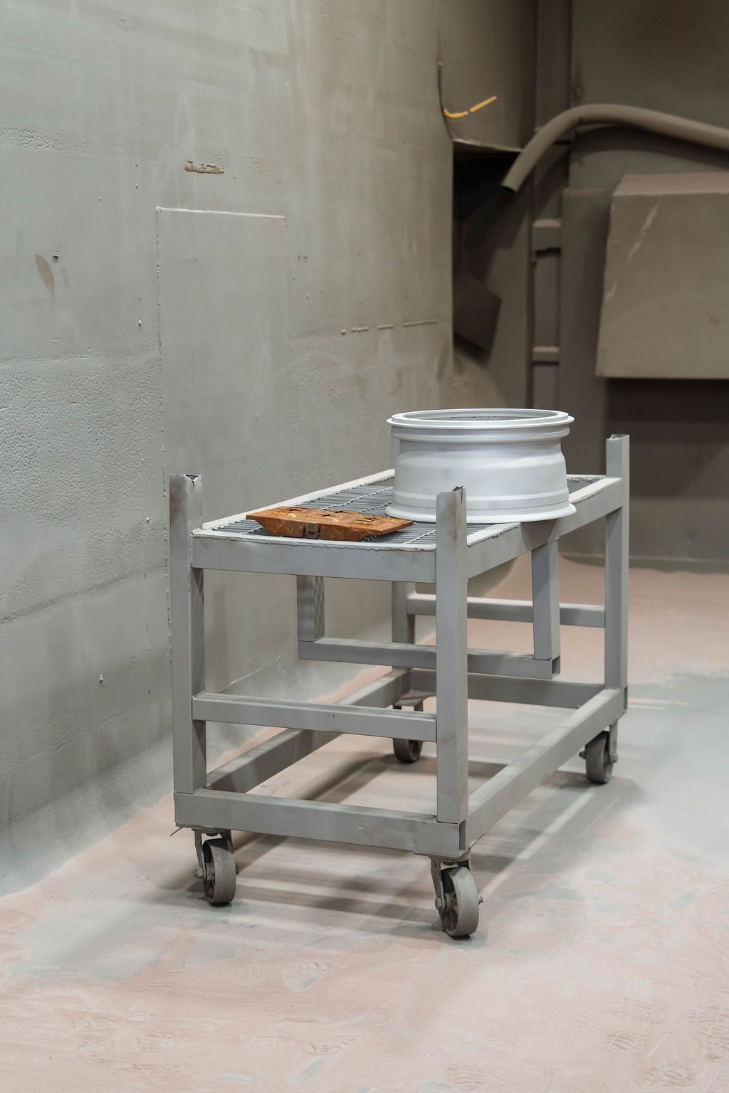 Gray utility cart with a metal bucket and tray in an industrial room