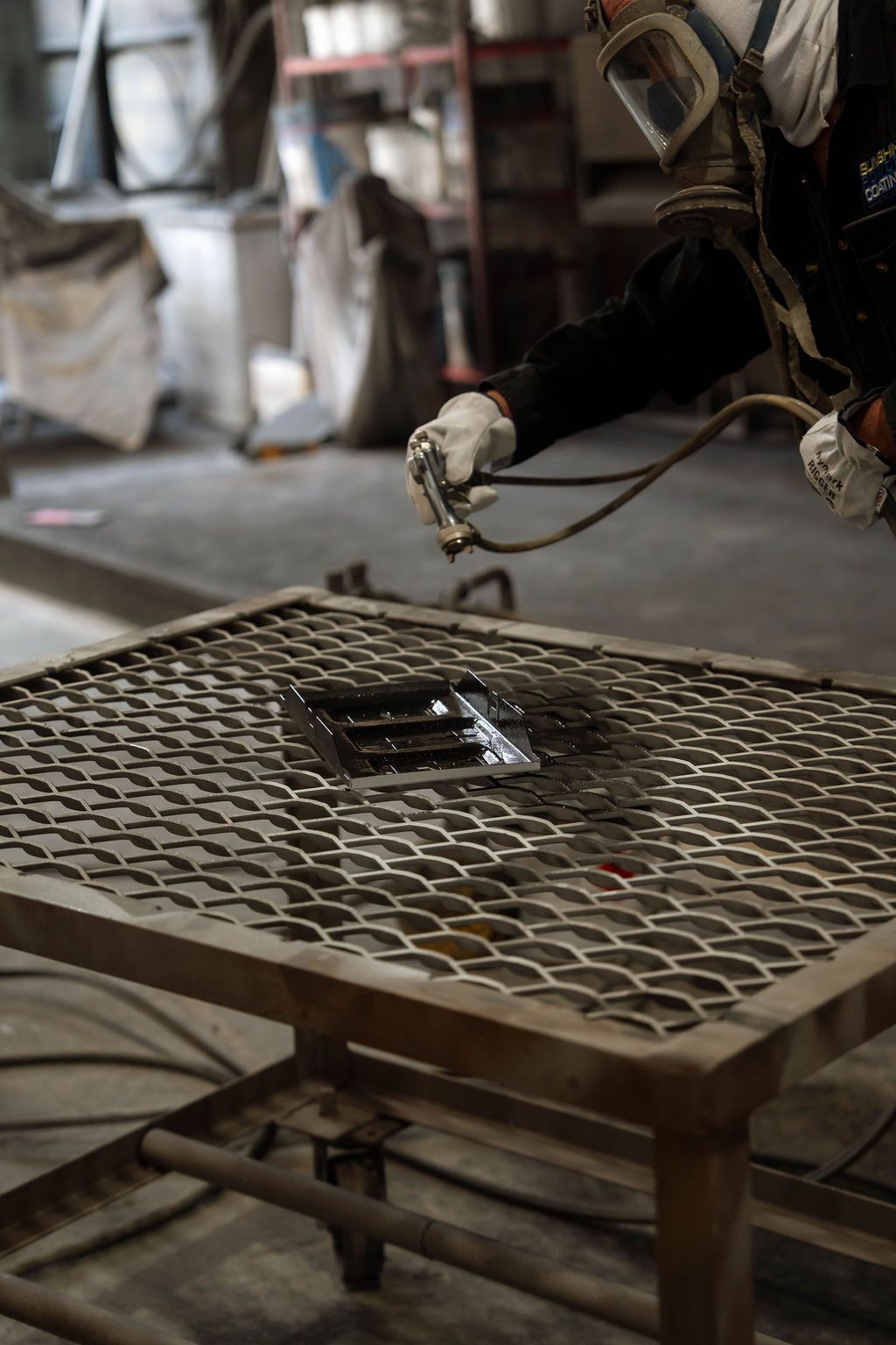 Metalworking robot arm welding a perforated steel table in a workshop