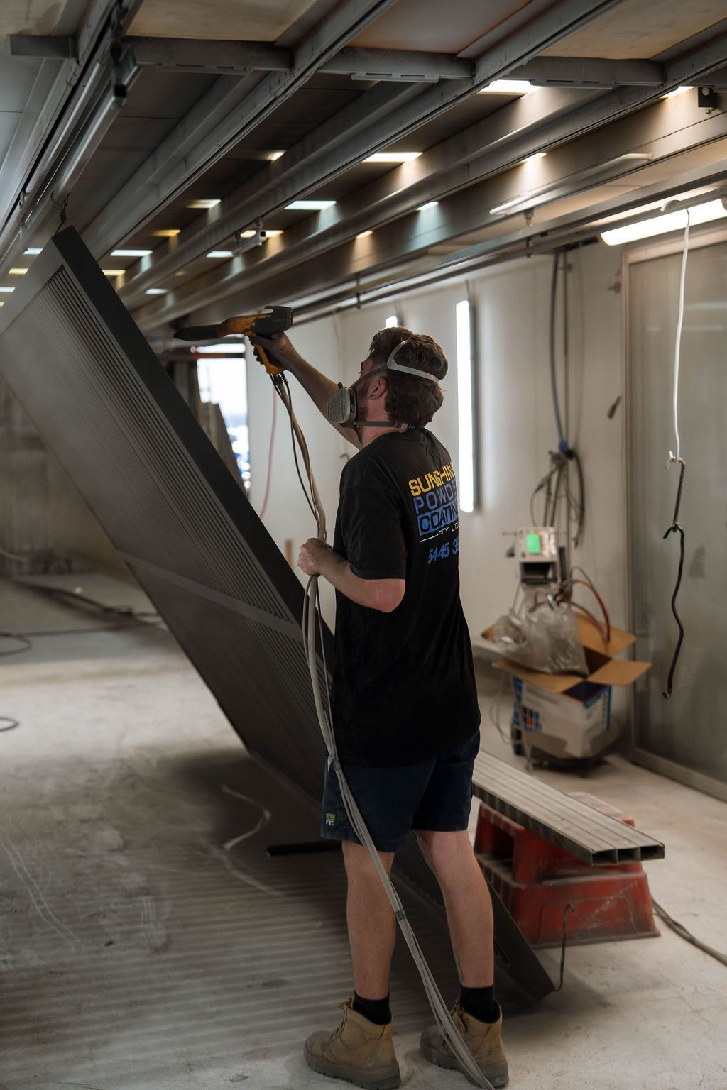 Worker in safety gear inspecting overhead ducting in an industrial space