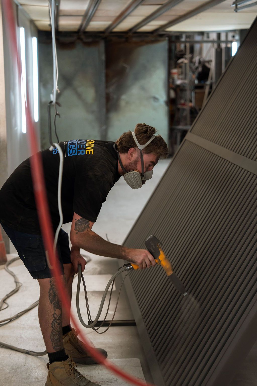 Worker spray-painting a large metal panel in an industrial workspace