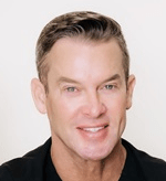 Professional headshot of Jerry Drinkard smiling in a white clinic coat, an aesthetics industry expert at Dr. Croley Aesthetic MD in Pace, Florida.
