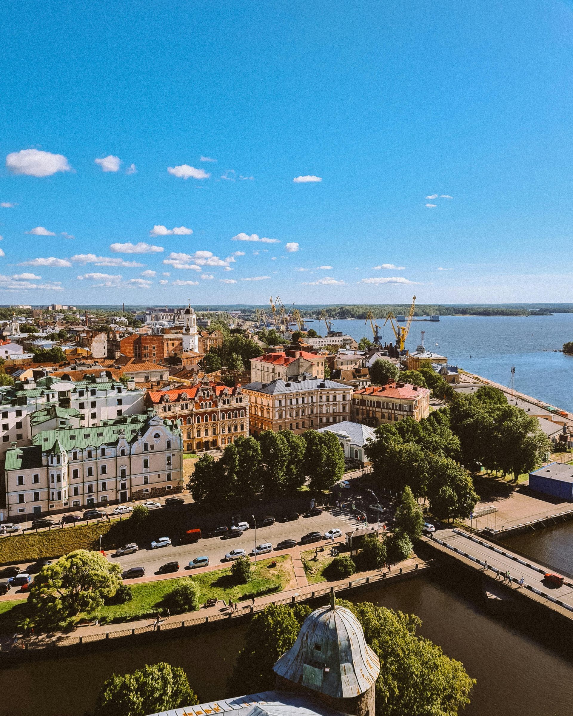 Aerial view of a colorful waterfront city with canals, bridge, harbor, and blue sky.