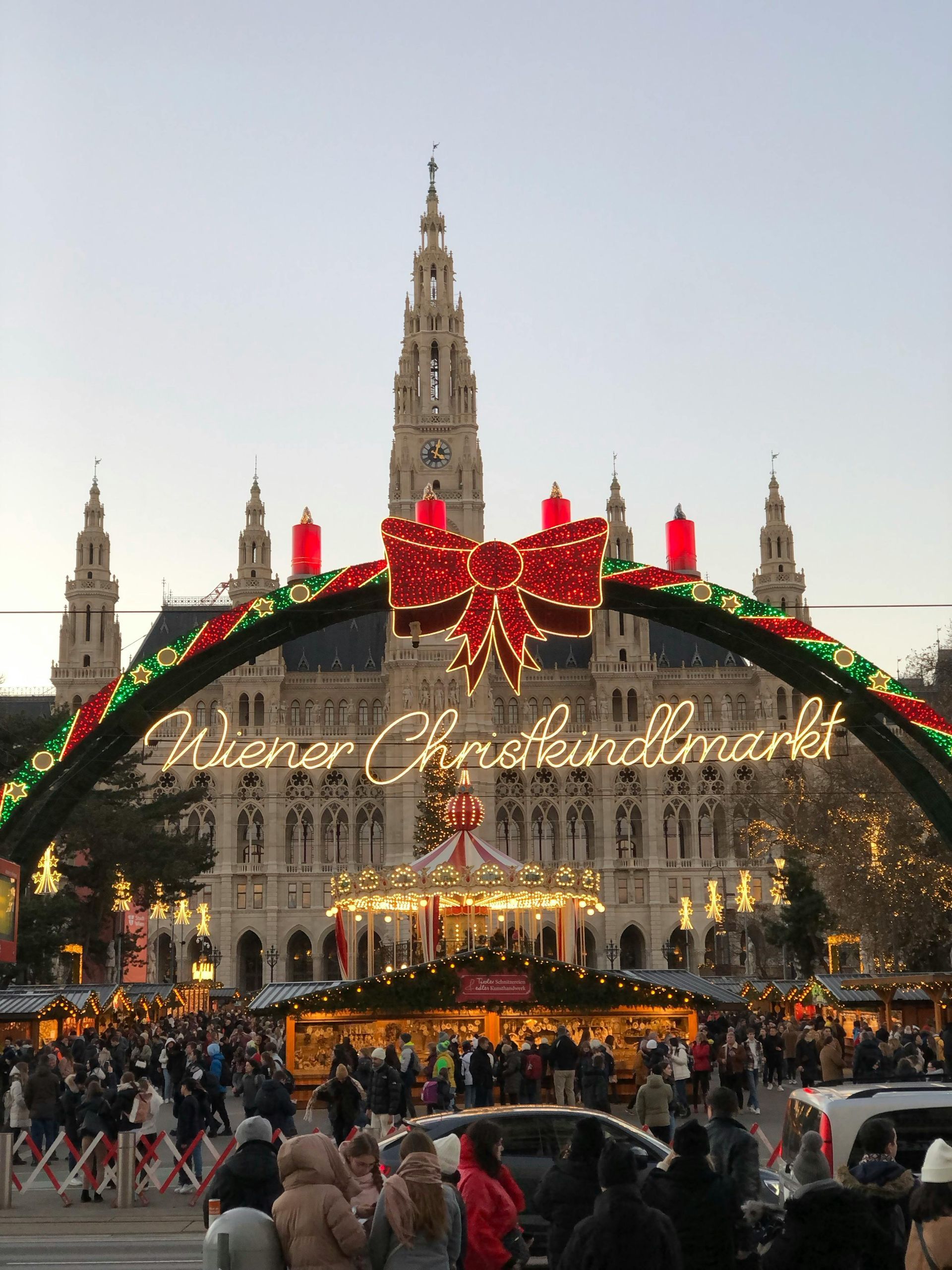 Nighttime Christmas market with a lit arch and grand cathedral in the background