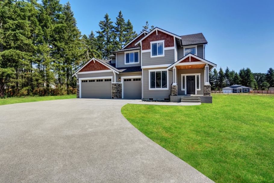 Modern two-story house with a paved driveway, balcony, and landscaped front yard