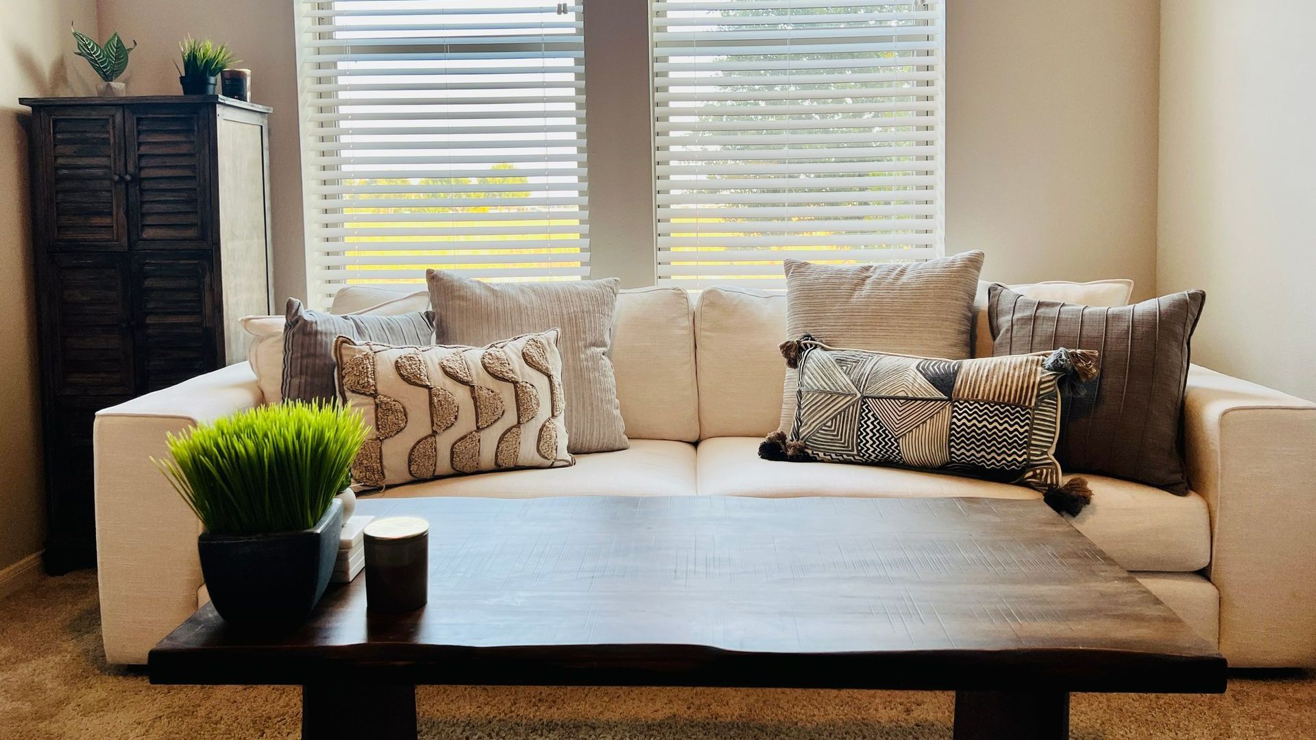 A living room with a couch , coffee table , and two windows. A living room with a couch and a coffee table.