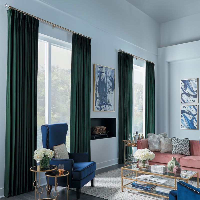 A living room with a couch , chair , table and green curtains.