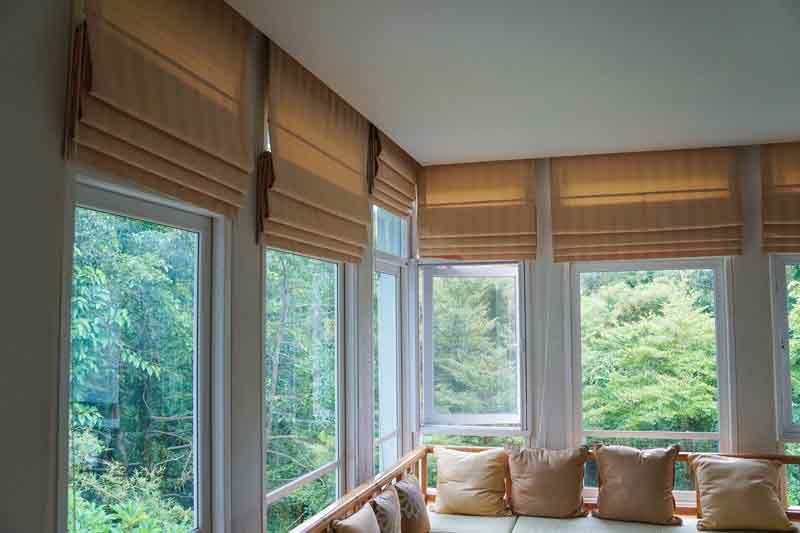 Custom Window Shades Pacific Palisades, CA A living room with a couch and lots of windows with roman blinds.