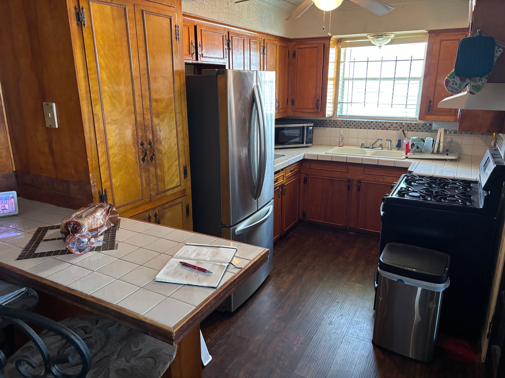 Kitchen with wood cabinets, stainless steel refrigerator, and tiled counter.