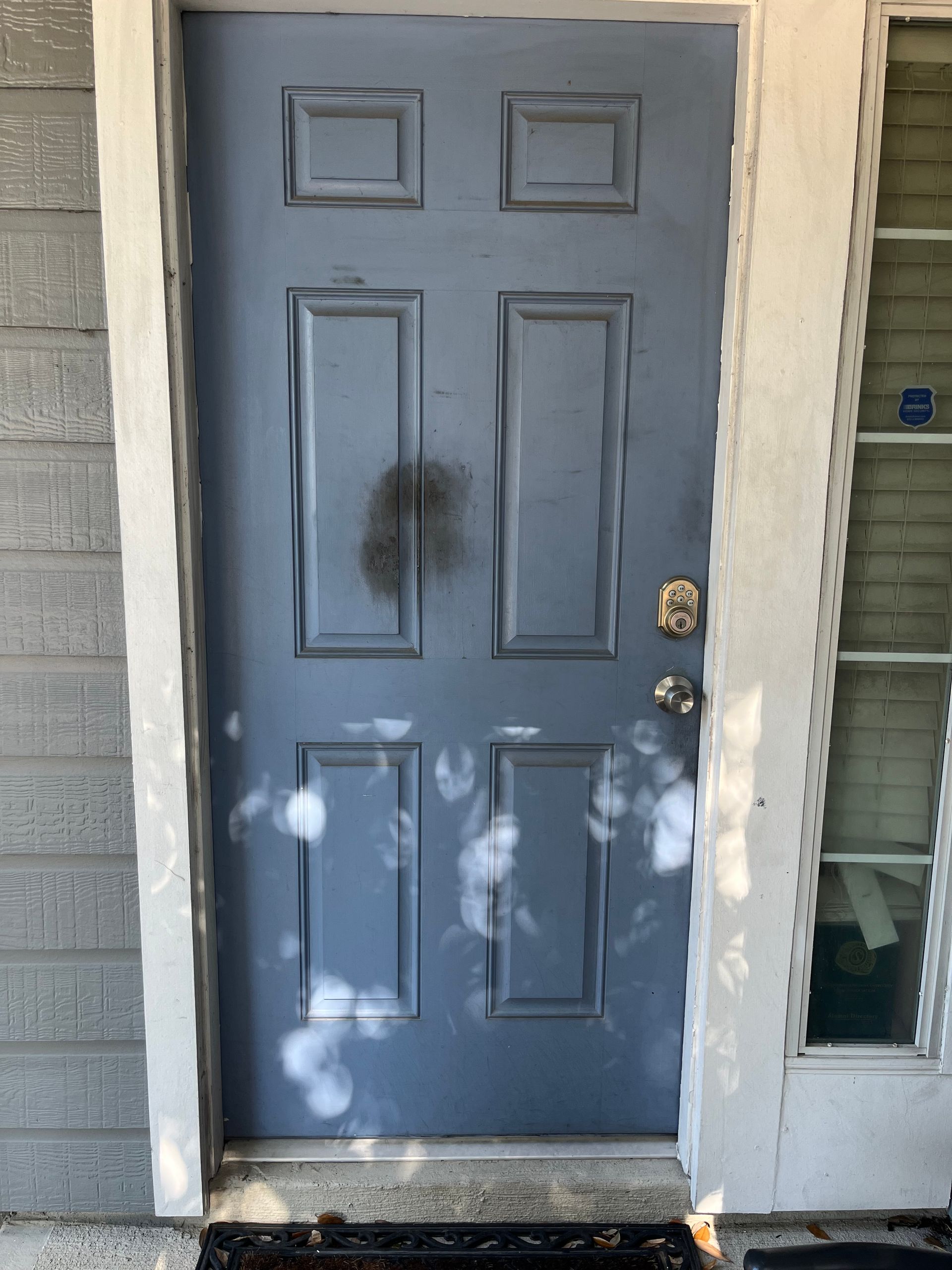 Blue front door with black stain near the center, framed by white trim and sidelights.