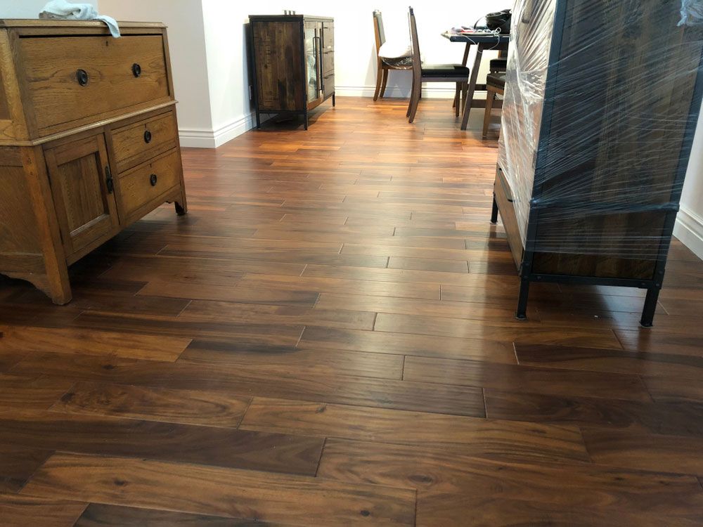 A Wooden Floor in a Living Room With a Dresser and Chairs — Bayside Carpets & Flooring in Kendall, NSW