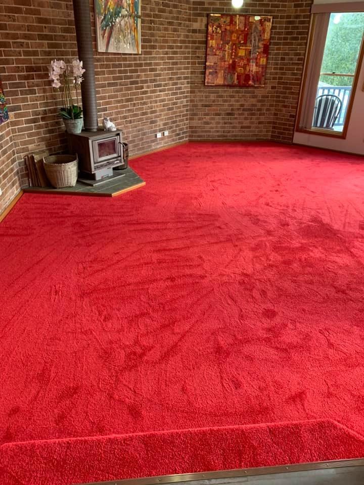 A Living Room With a Red Carpet and a Fireplace — Bayside Carpets & Flooring in Laurieton, NSW