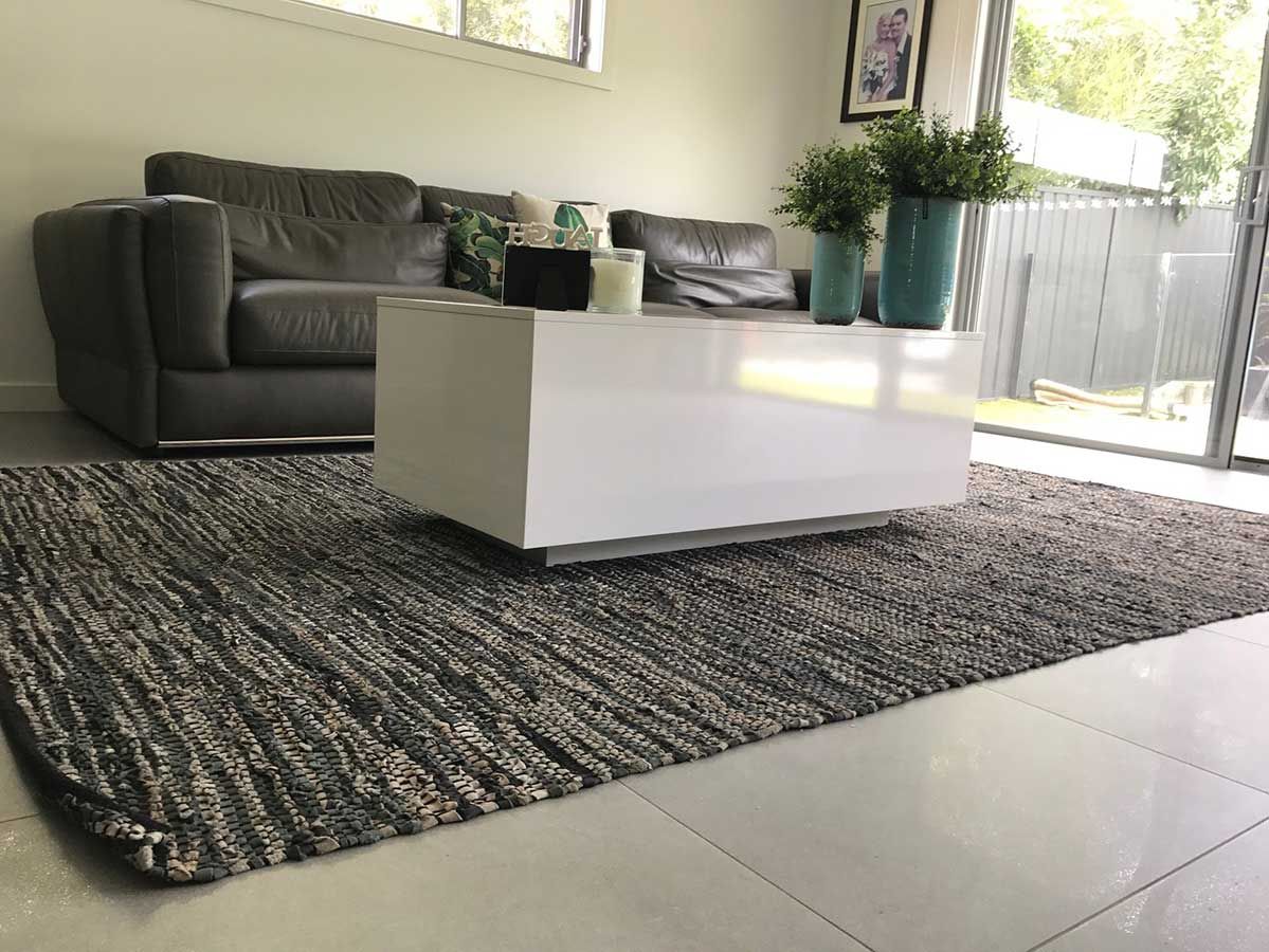 A Living Room With a Couch, Coffee Table, and Rug — Bayside Carpets & Flooring in Bonny Hills, NSW