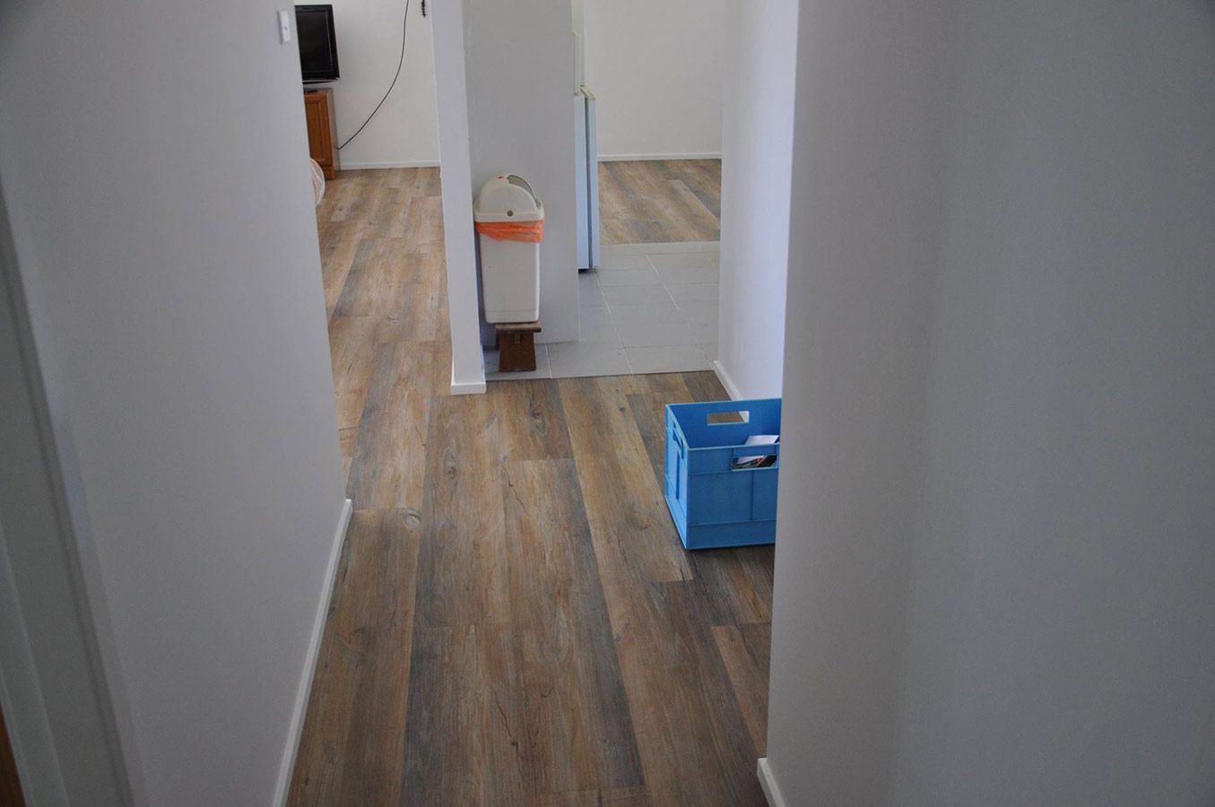 A Hallway With Wooden Floors and a Blue Box on the Floor — Bayside Carpets & Flooring in Laurieton, NSW