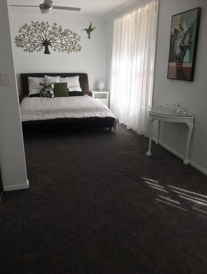 A Bedroom With a Large Bed and a Ceiling Fan — Bayside Carpets & Flooring in Harrington, NSW