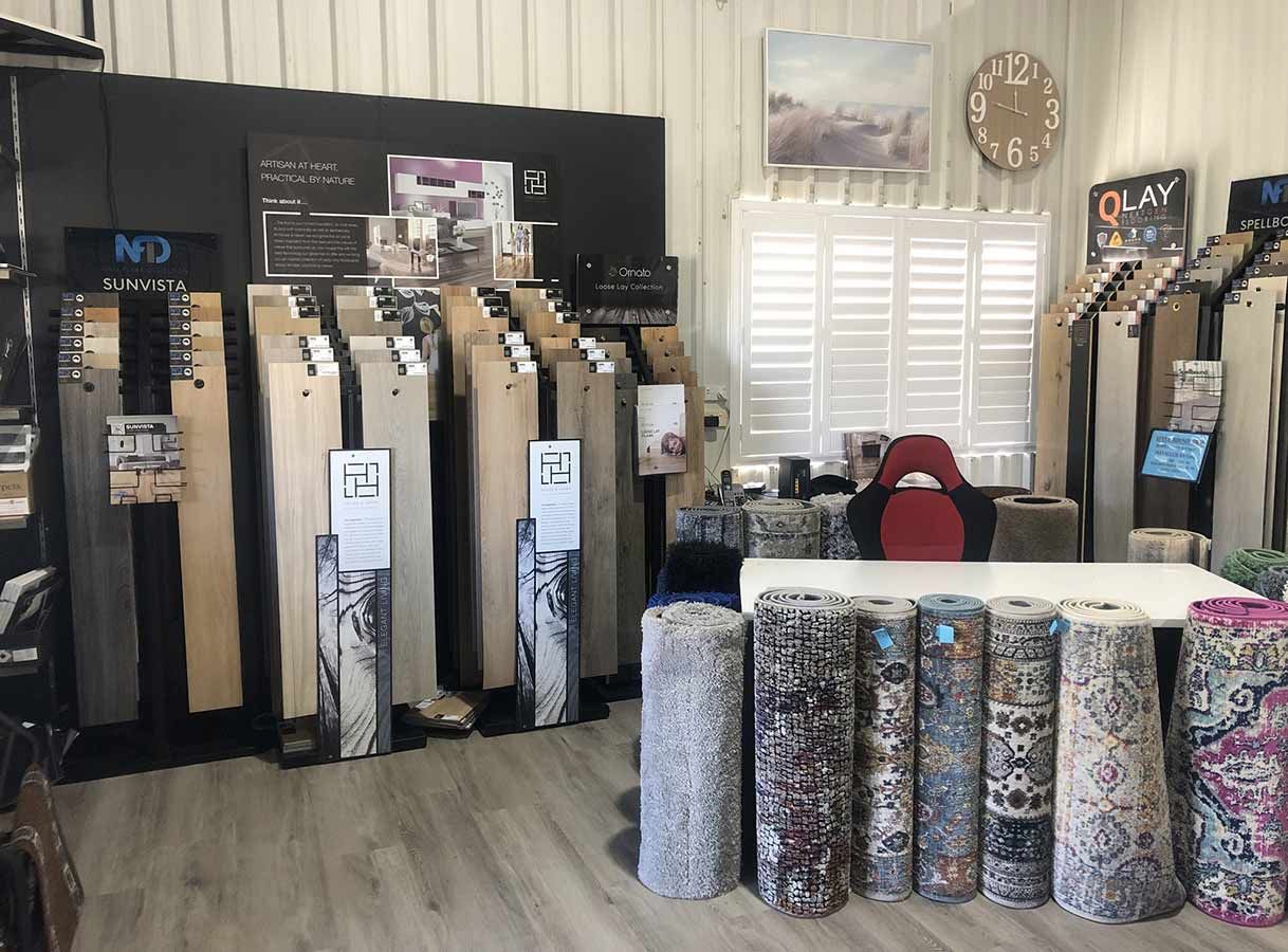 A Room Filled With Rolls of Carpets and a Table — Bayside Carpets & Flooring in Laurieton, NSW