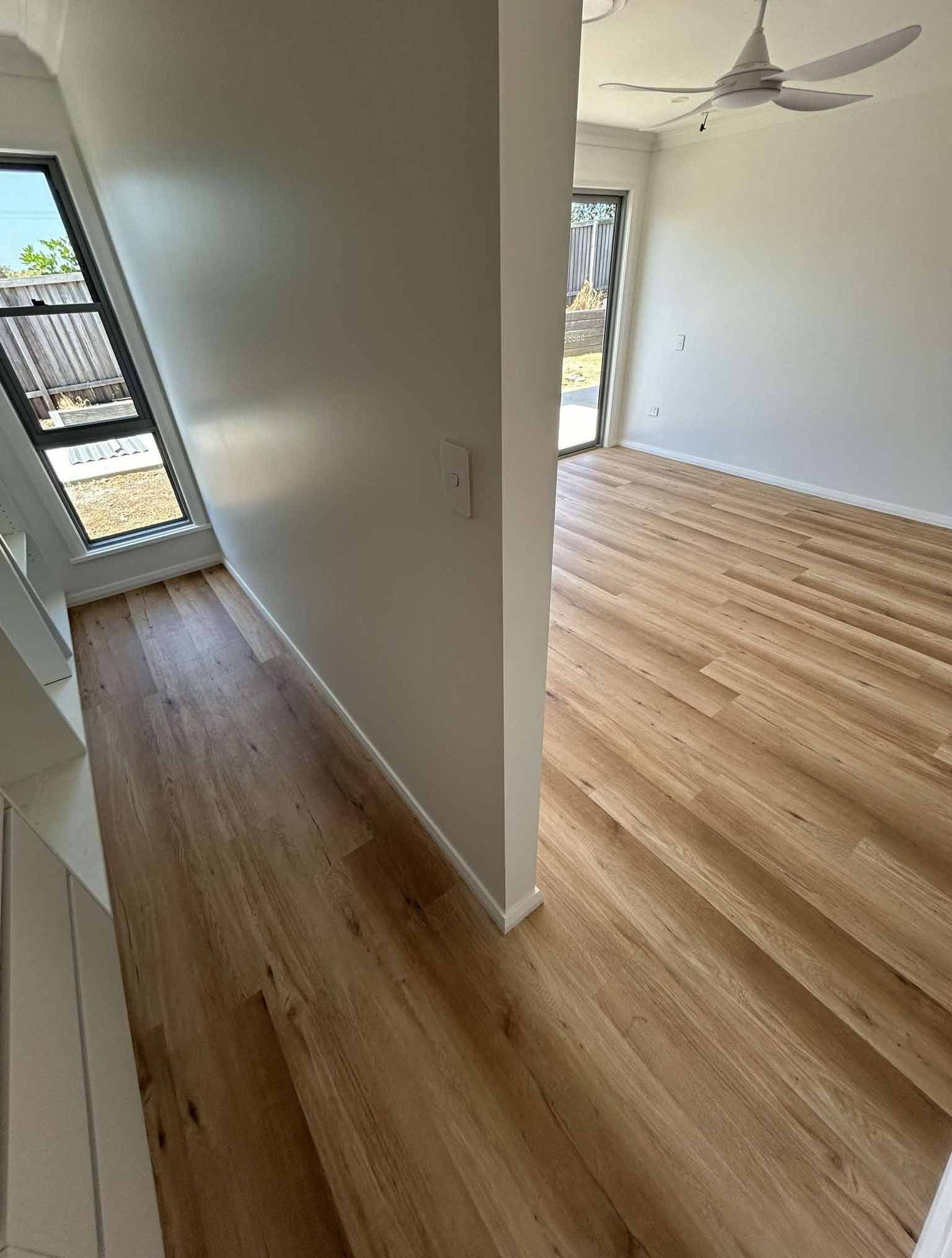 A Hallway in a House With a Wooden Floor and a Ceiling Fan — Bayside Carpets & Flooring in Laurieton, NSW