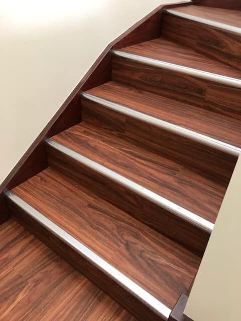 A Close Up of a Wooden Staircase With a Metal Railing — Bayside Carpets & Flooring in Laurieton, NSW