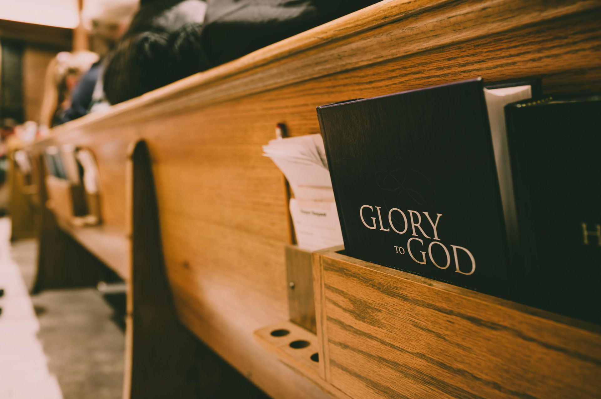 A bible is sitting on a wooden shelf in a church.