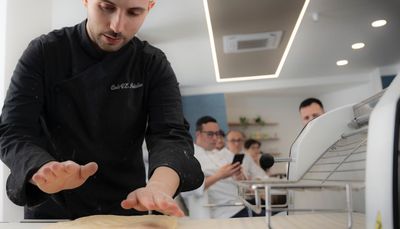 Un uomo dimostra un'attività pratica in un ufficio luminoso, con i colleghi che lo osservano nelle vicinanze.