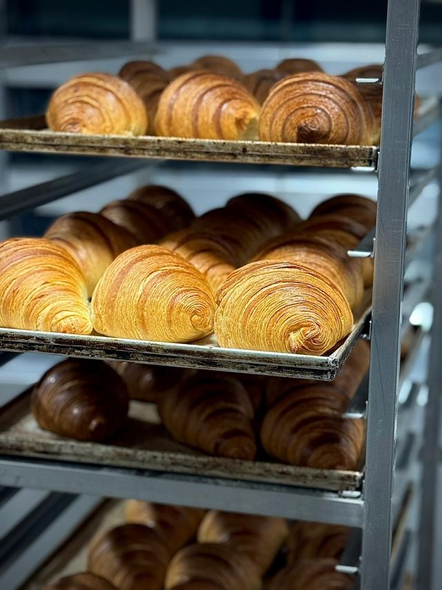 Una pagnotta di pane rustico a fette su un tagliere di legno, con uno sfondo sfocato di una cucina.