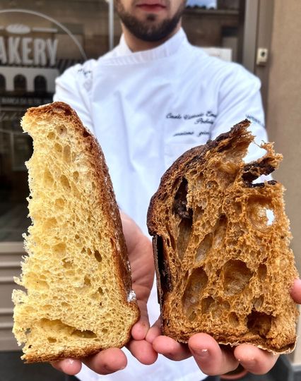 Pasticcini dorati a forma di fiore, ricoperti di gocce di cioccolato, disposti su un vassoio scuro sopra un telo verde.