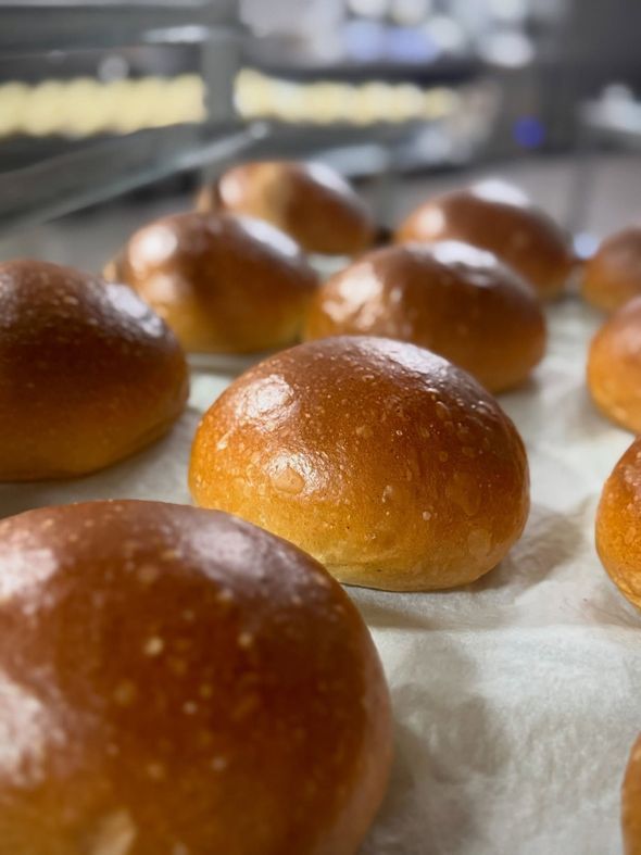 Panini appena sfornati, dorati e croccanti, che si raffreddano su carta da forno nella cucina di un panificio.