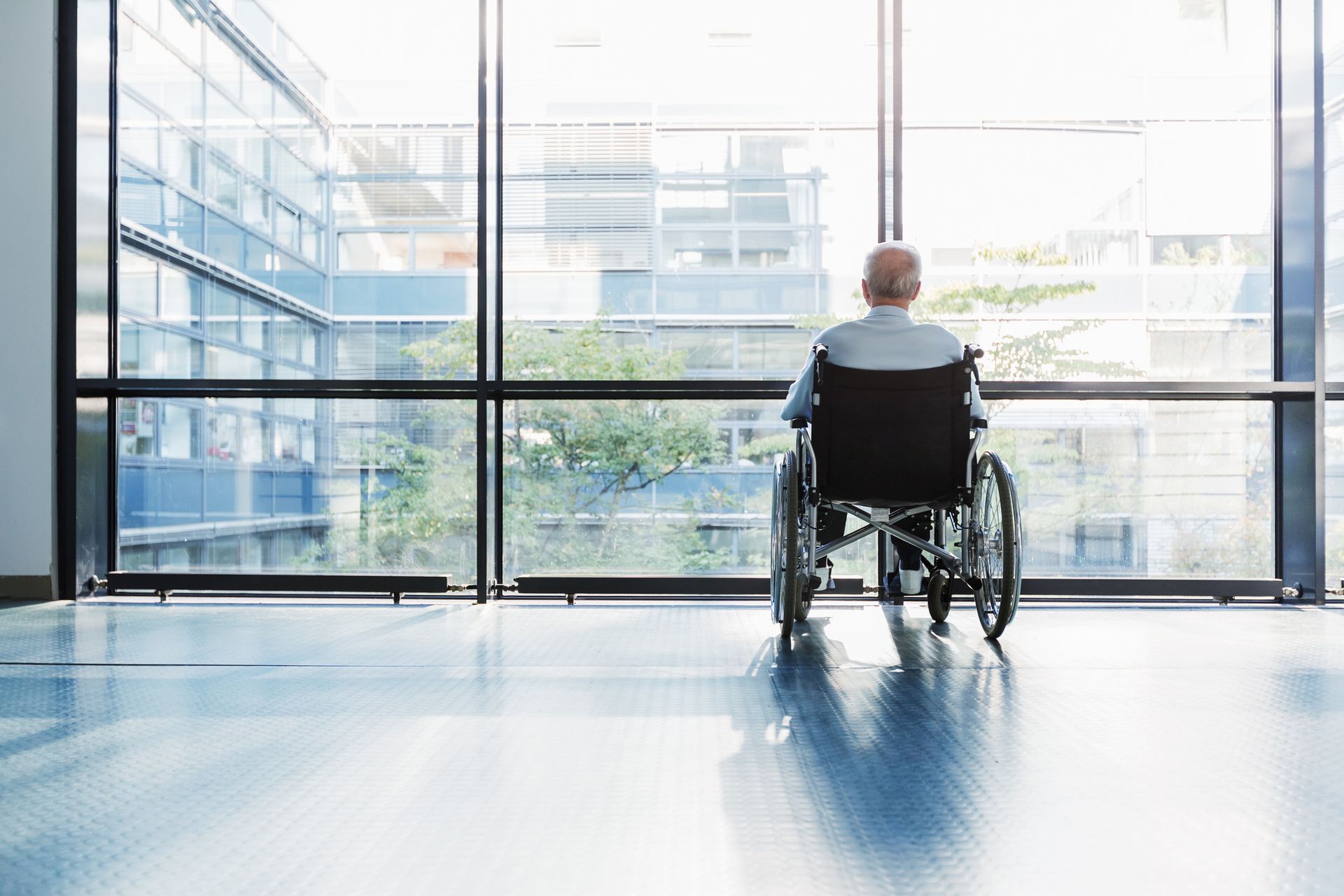 A man in a wheelchair is looking out of a window.