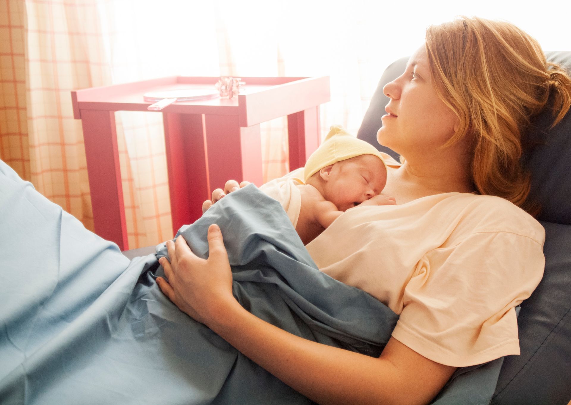 A woman is laying in a hospital bed holding a newborn baby.