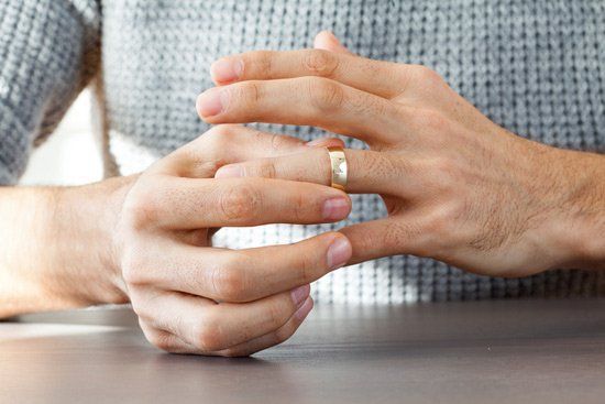 Person removing wedding ring from finger.