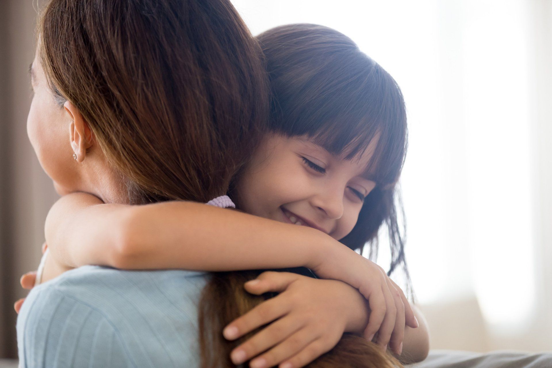 Little Girl Hug Young Mom —Wilmington, NC — Allan Brandon Tise PLLC Child embracing a person; both smiling.