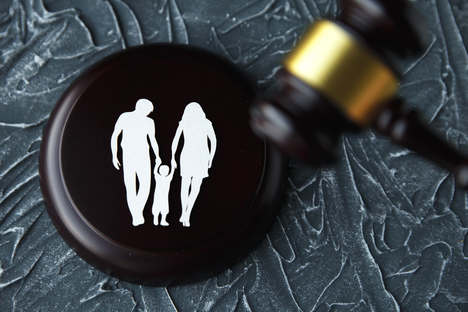 Gavel next to a wooden block with a family silhouette, symbolizing family law or court.