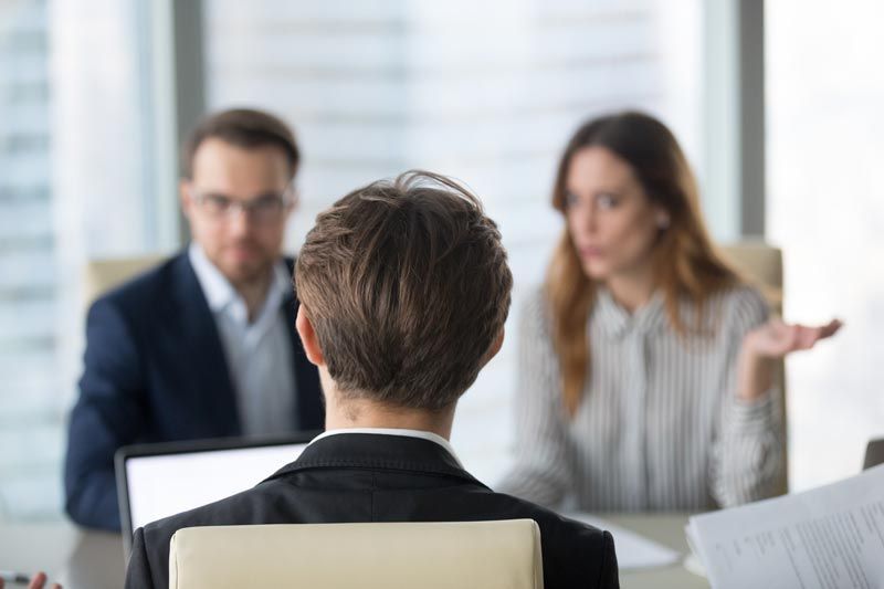 Middle Aged Couple Talking to Lawyer — Wilmington, NC — Tise Allan Brandon Person in suit facing two people at a table, woman gestures, man looks on, business setting.