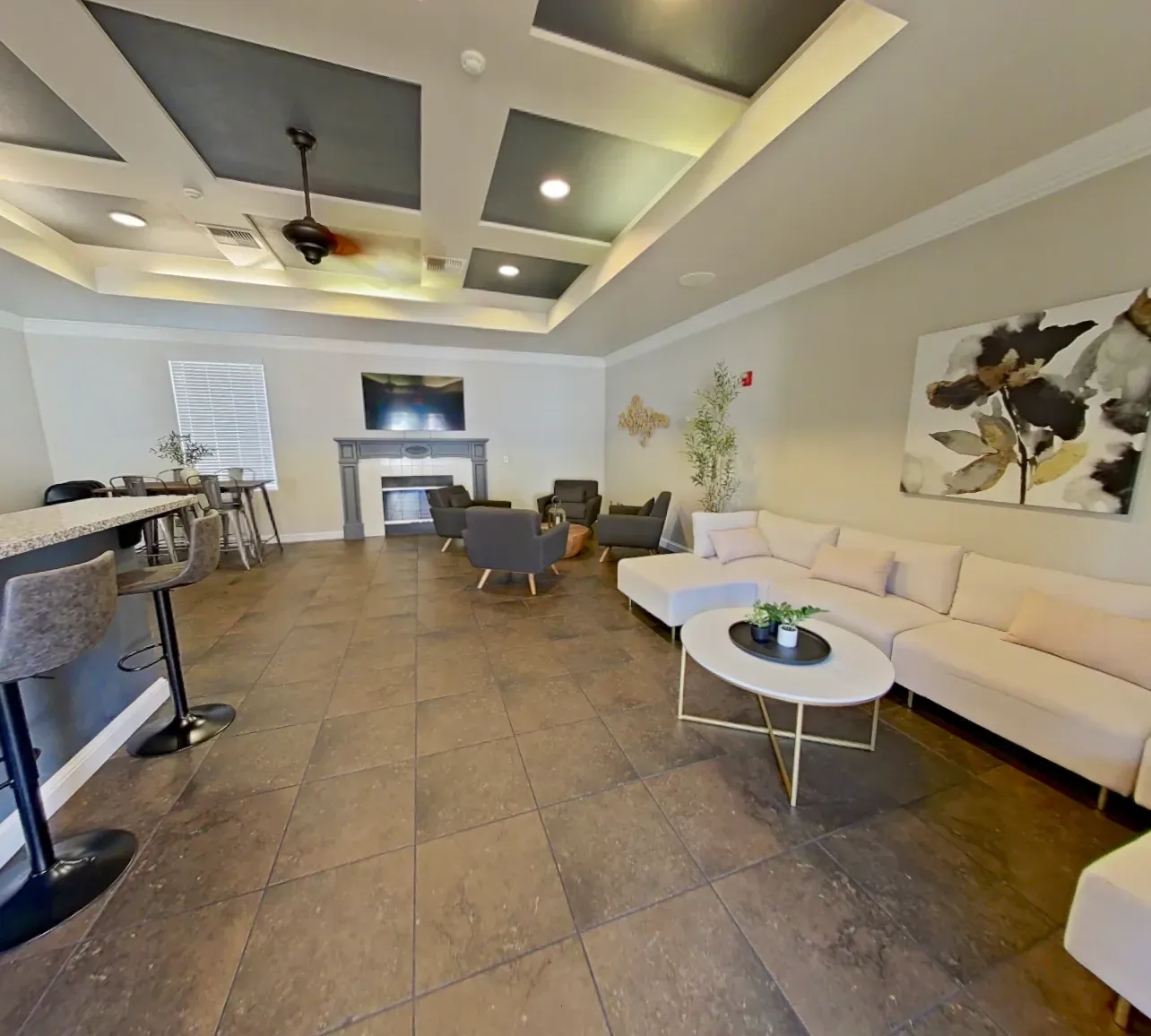 Spacious community lounge with a modern sectional sofa, coffee table, and a bar area with stools.