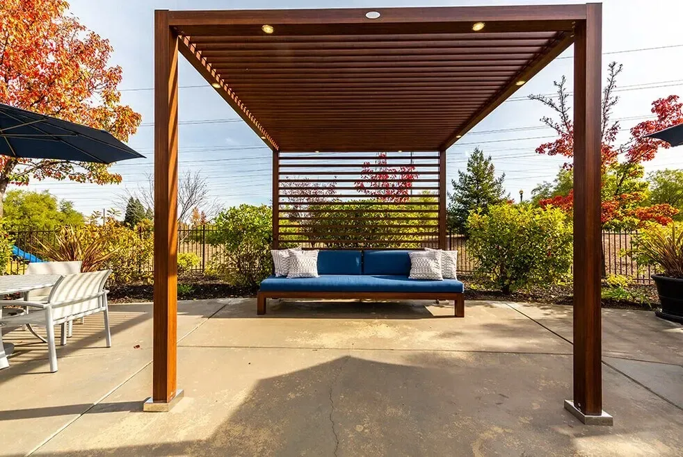 Outdoor seating area with a wooden pergola and blue couch.