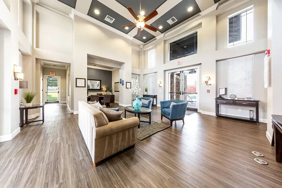 Spacious modern lobby with seating areas, a high ceiling with a fan, and large glass doors leading outside.