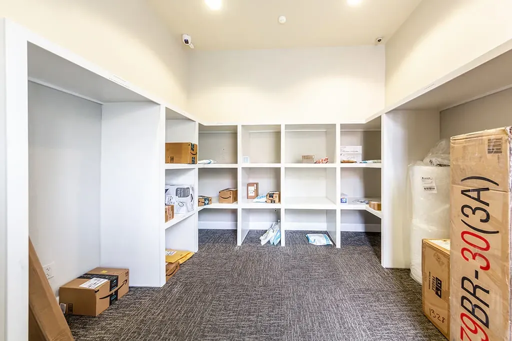 Package room with shelves for deliveries and boxes on the floor.