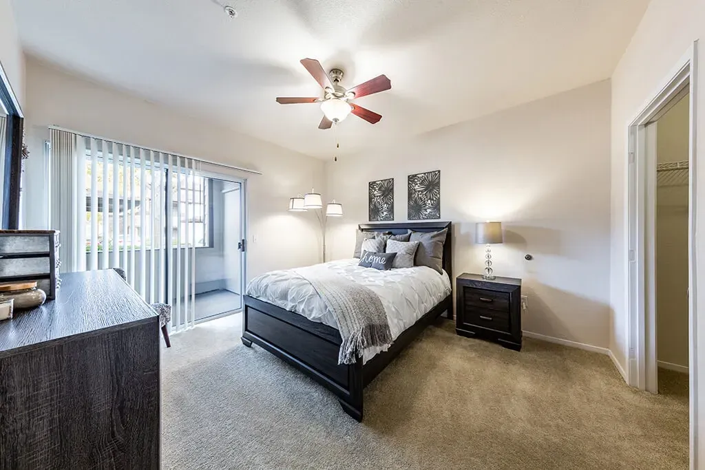 Stylish bedroom with a queen-size bed, dresser, and sliding glass door.