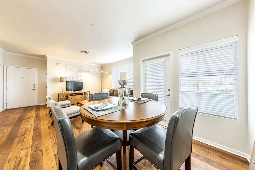 Dining area and living room in an apartment with hardwood floors and natural light.