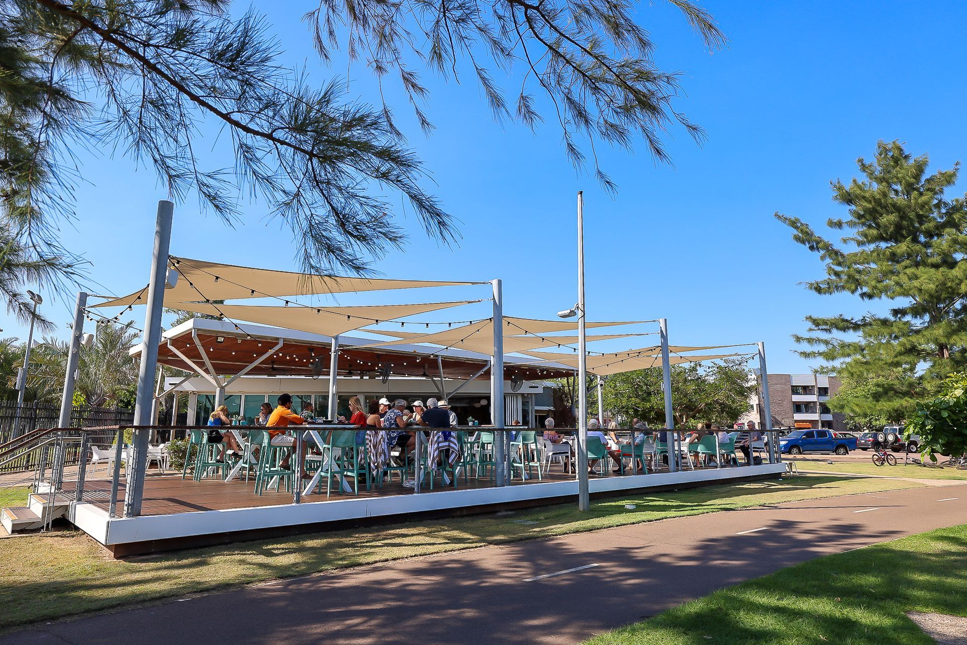 Outdoor cafe with tan canopies and people seated at tables on a sunny day — Invision NT in Coconut Grove, NT