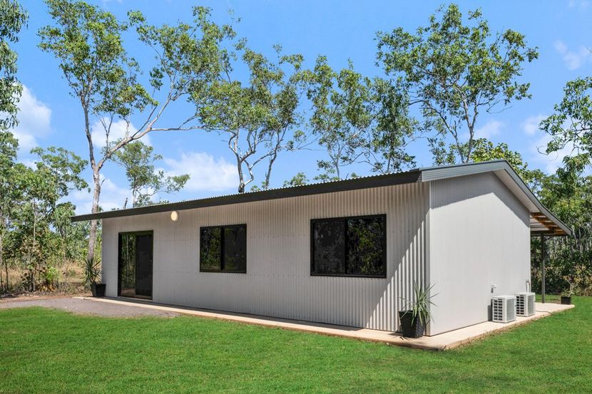 Single-story modern white house with dark windows and a green lawn under blue sky — Invision NT in Gove, NT