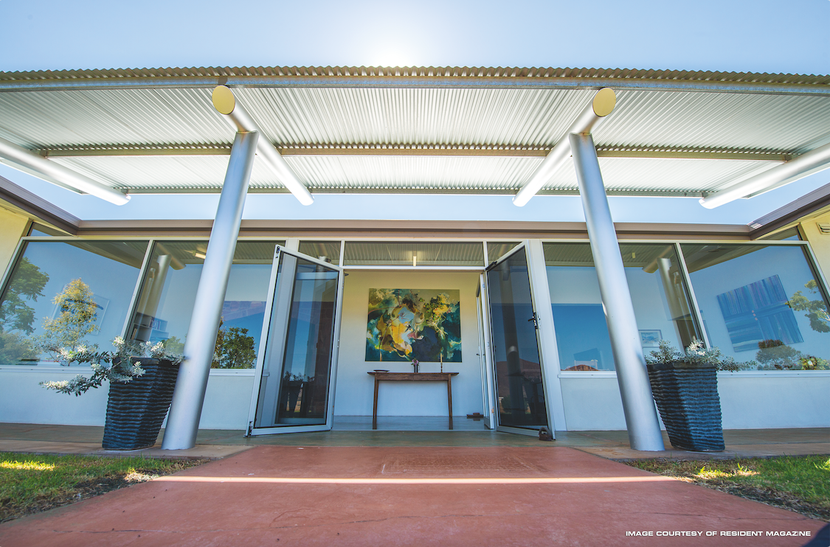 Modern building entrance with glass walls, white columns, and a central artwork above the doorway — Invision NT in Gove, NT