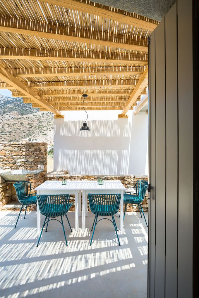 A dining room with a table and chairs under a thatched roof.