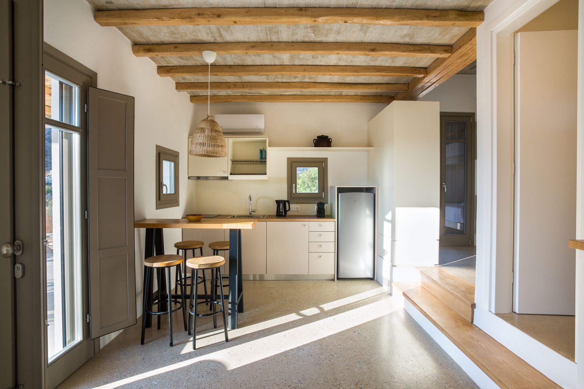 A kitchen with a table and stools and a refrigerator.