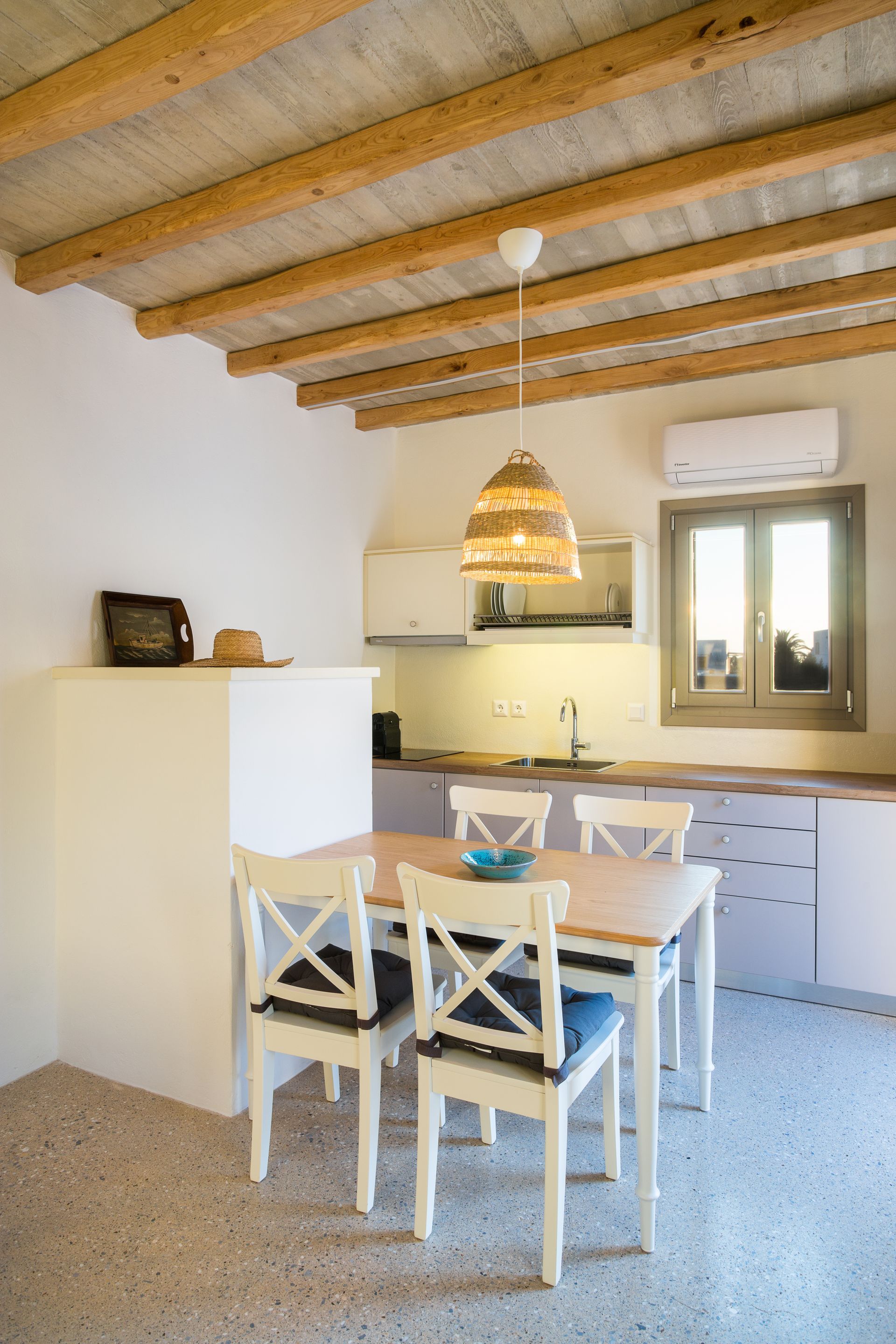 A kitchen with a table and chairs and a ceiling with wooden beams.