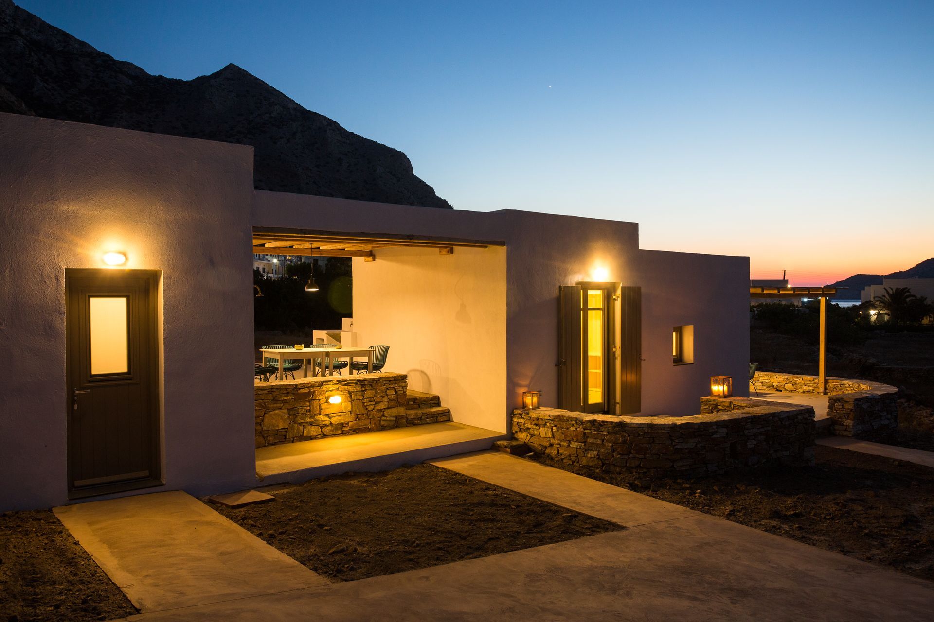 A house is lit up at night with a mountain in the background.