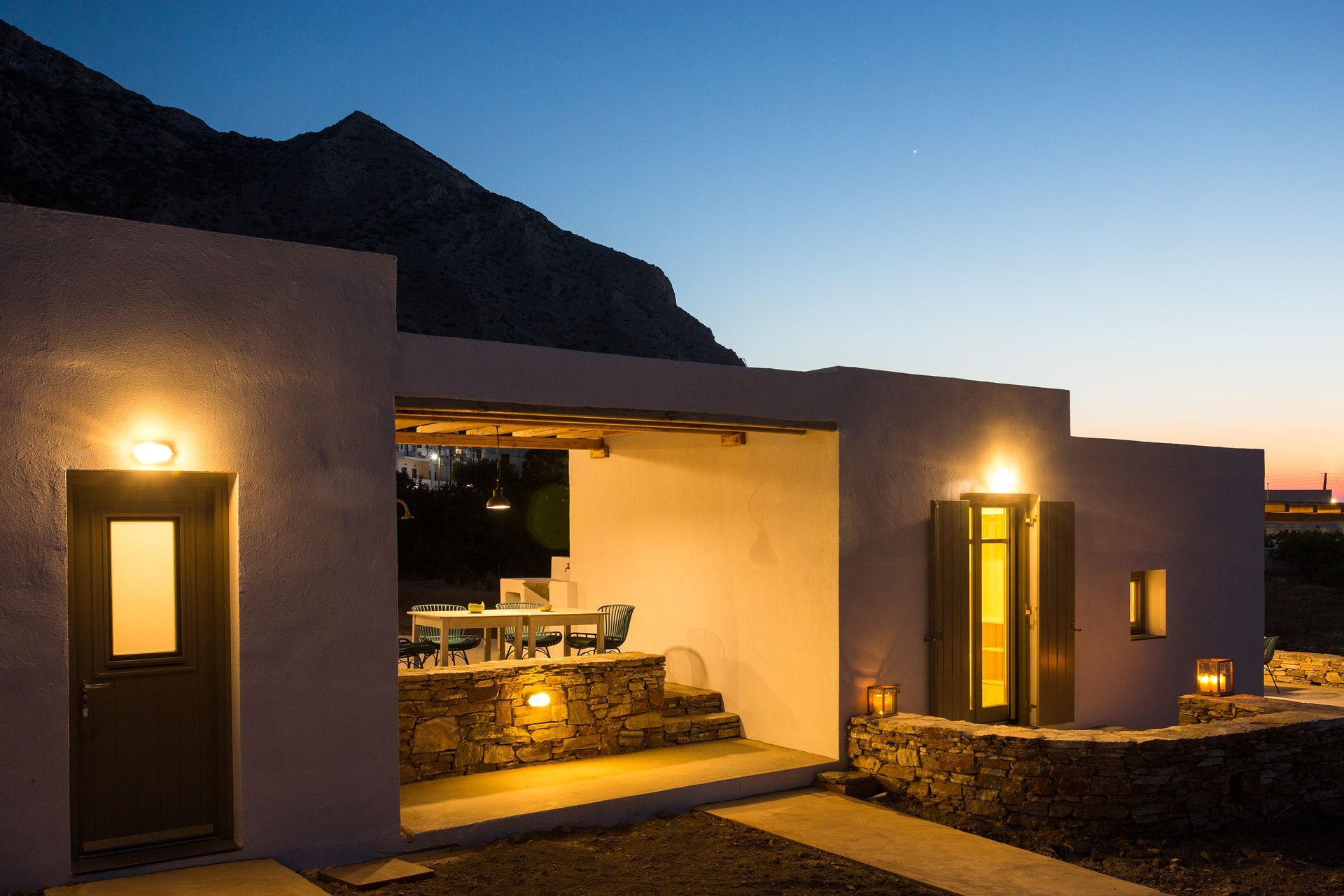 A house is lit up at night with a mountain in the background